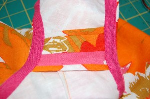 This shows a shoulder seam with a Hong kong finish to the raw edges and the pink bias binding around the armhole and neck.