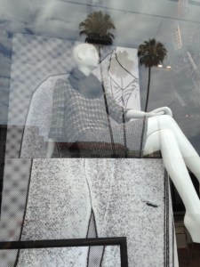 The reflection of palm trees in the window obscures some of the fashions.