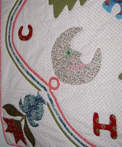 A smiling moon, with rick rack mouth and a green button eye.