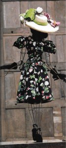 Made from black crepe de Chine printed with daisies and butterflies, trimmed with white lace rosette. The black suede gloves are by Hermes, while the straw boater is by Rose Valois.